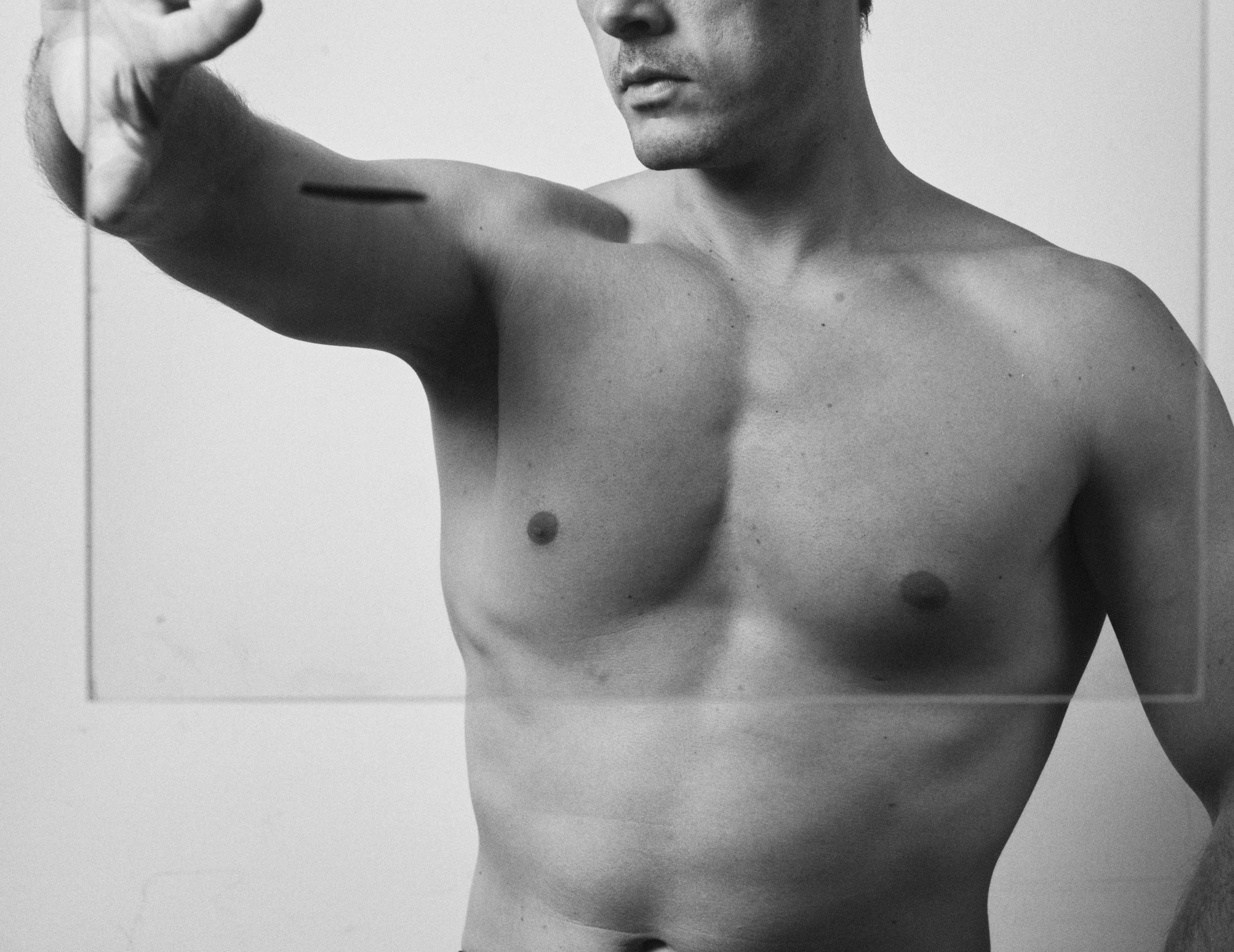 naked male torso facing mirror