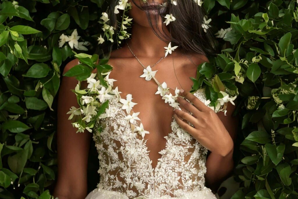 Woman surrounded by jasmine blossoms in a white floral dress, illustrating why florals read as feminine